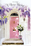 The photograph shows a sunlit entrance in Honor Oak that feels poised perfectly between calm and celebration. A softly painted pink front door, in a muted, rosy tone, stands at the heart of the scene, its surface slightly textured, suggesting the careful brushstrokes of a recent refresh-perhaps to mark a move into a new home near Honor Oak Park. The door is set within pale, whitewashed walls that reflect the gentle daylight, while a matching, lightly tinted shutter adds balance on one side, giving the façade a quiet, storybook charm. Draped above and partly to the side is a luxuriant curtain of wisteria, its blossoms a dreamy mix of lavender and soft purple. The long, loose clusters of flowers tumble over the entrance, catching the light in places and falling into soft, lilac shadows in others, much like the wisteria that brightens many SE23 terraces in late spring. Resting neatly at the doorstep is a vintage-style metal bucket, carefully placed as if just delivered by a local florist serving the Honor Oak and Brockley Rise area. It brims with white and cream roses, their petals full and velvety, some blooms wide open, others just starting to unfurl. Gentle sprays of toned-down greenery weave through the arrangement, giving it movement and a natural, gathered-from-the-garden feel. A pale pink ribbon, tied around the bucket, completes the composition with a tender, romantic touch. The overall mood is warm and inviting, a floral still life that quietly celebrates the joy, hope, and sense of possibility that come with crossing the threshold of a new home in Honor Oak.